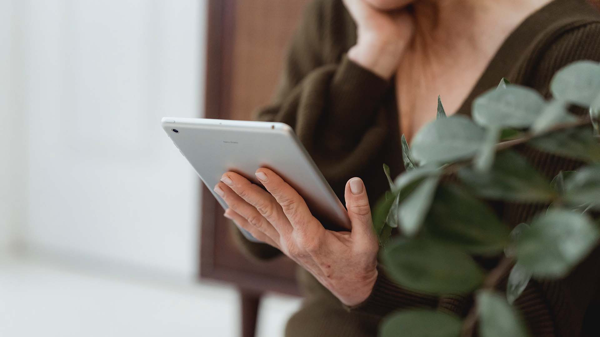 Person som leser nyhetsbrev på nettbrett om rekruttering, arbeidsinkludering og sykefravær fra Fønix
